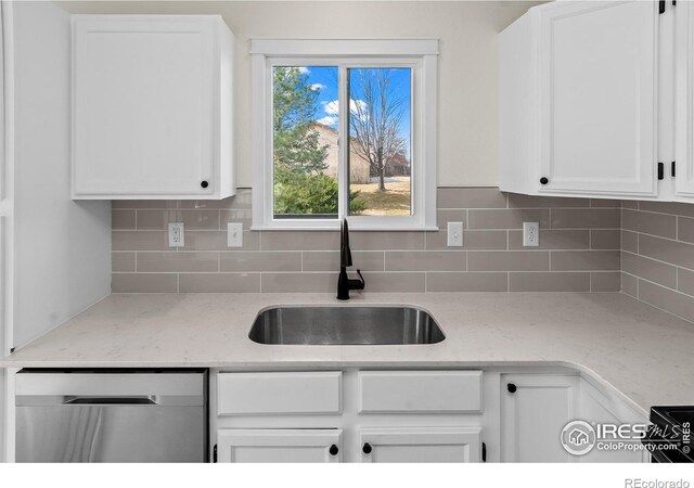 kitchen with light stone counters, a sink, white cabinetry, backsplash, and dishwasher