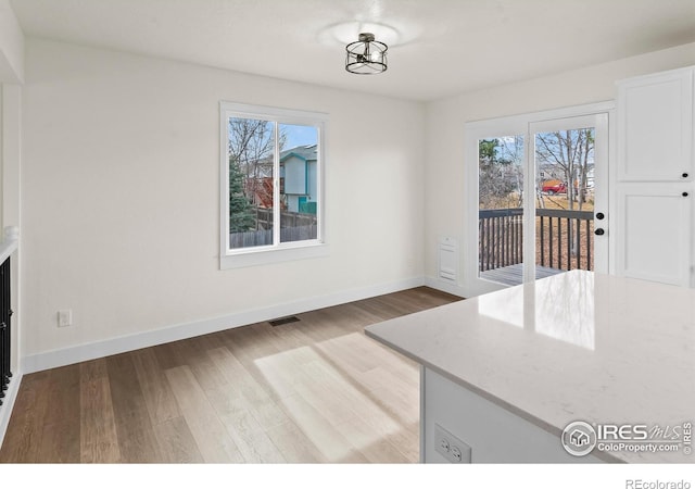 unfurnished dining area featuring light wood-style flooring, visible vents, and baseboards