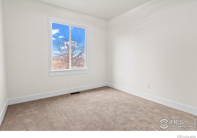 unfurnished room with carpet, visible vents, and baseboards