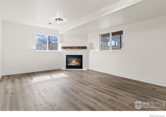 unfurnished living room featuring a wealth of natural light, baseboards, and wood finished floors