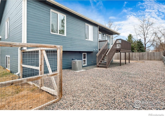 back of property with a deck, cooling unit, fence, and stairway