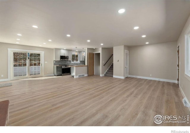 unfurnished living room featuring recessed lighting, visible vents, light wood-style floors, and stairs