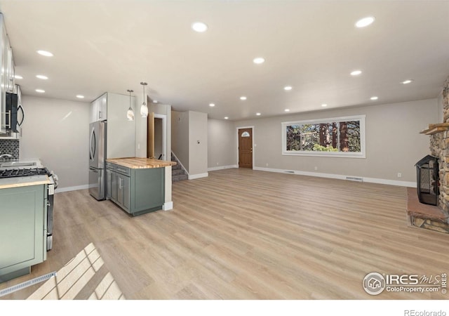 kitchen featuring green cabinets, wood counters, light wood finished floors, and stainless steel appliances