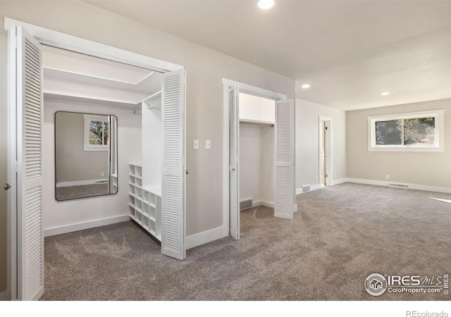 unfurnished bedroom featuring recessed lighting, visible vents, carpet floors, and multiple closets