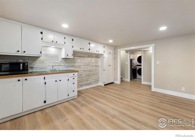 kitchen with recessed lighting, light wood-type flooring, white cabinets, and stacked washing maching and dryer