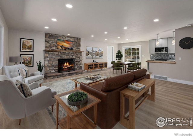 living area with light wood-type flooring, visible vents, recessed lighting, a fireplace, and baseboards