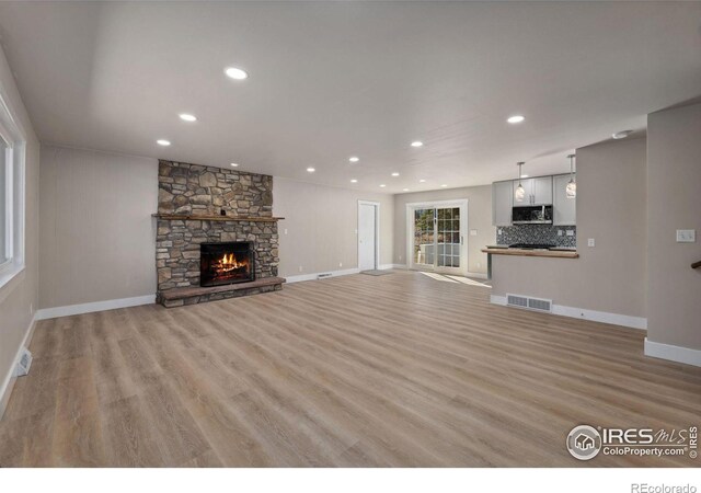 1059 Lexington Ln, Estes Park, CO 80517 - unfurnished living room with a stone fireplace, light wood-style flooring, recessed lighting, and baseboards