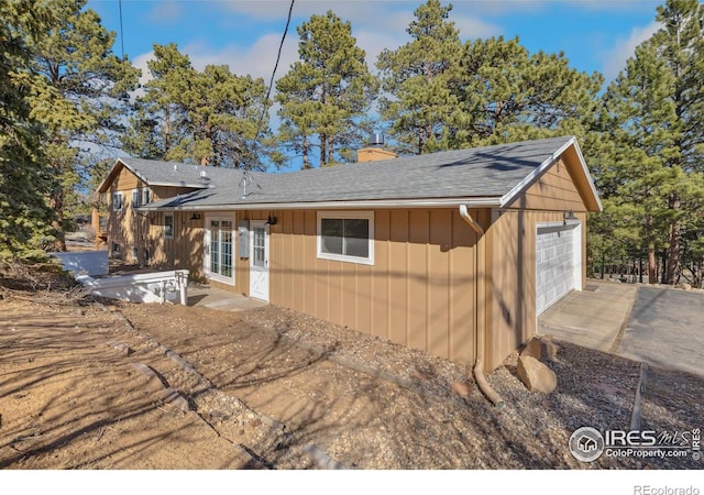 1059 Lexington Ln, Estes Park, CO 80517 - view of front of house with a chimney, a shingled roof, a garage, driveway, and board and batten siding