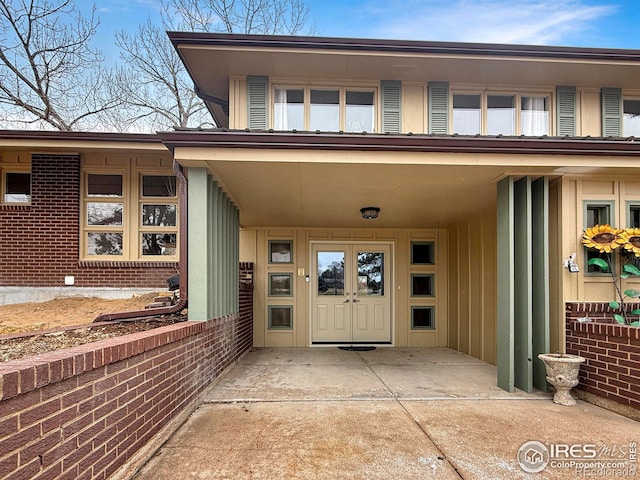 doorway to property with a carport, board and batten siding, and brick siding