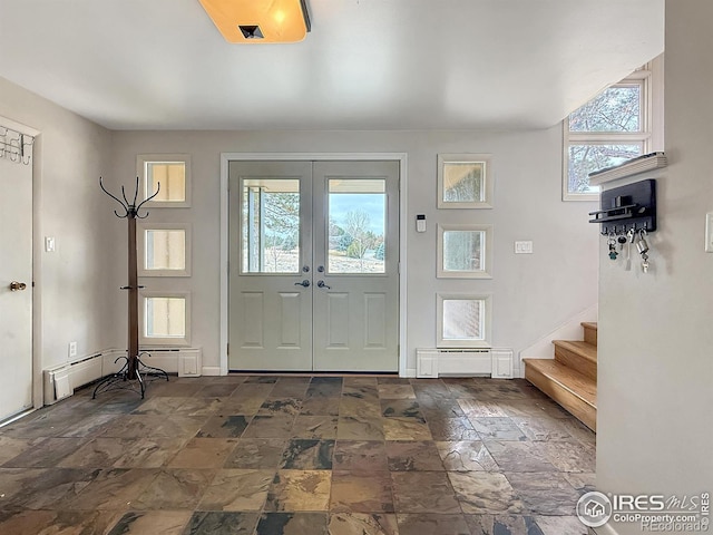 foyer entrance featuring a baseboard radiator, stone tile flooring, french doors, and stairs