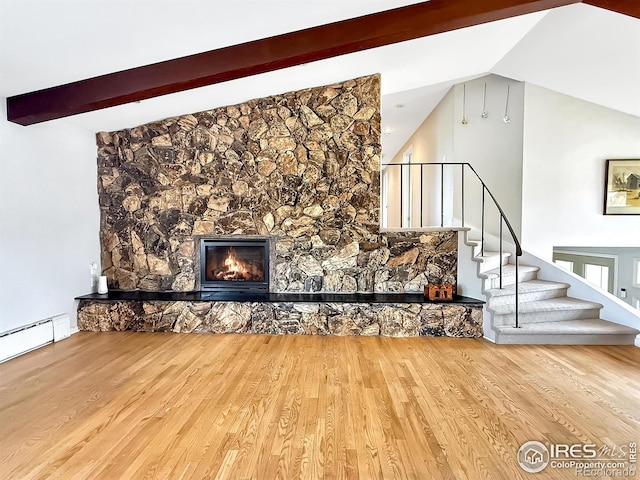 unfurnished living room with lofted ceiling with beams, stairs, wood finished floors, and a stone fireplace