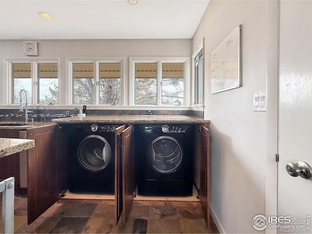 clothes washing area featuring recessed lighting, stone finish flooring, a sink, separate washer and dryer, and baseboards