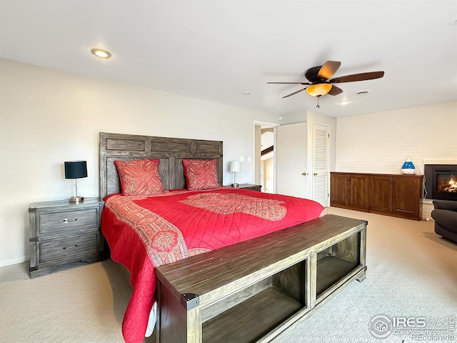 carpeted bedroom with recessed lighting, baseboards, a ceiling fan, and a glass covered fireplace