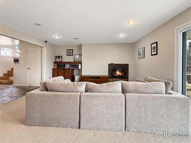 living area featuring a premium fireplace, stairway, and recessed lighting