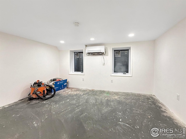 unfurnished room featuring unfinished concrete flooring, a wall unit AC, and recessed lighting