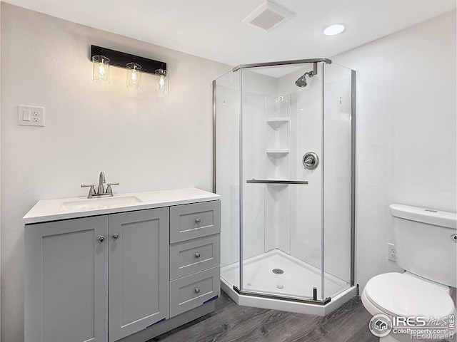 full bathroom featuring visible vents, toilet, wood finished floors, vanity, and a shower stall