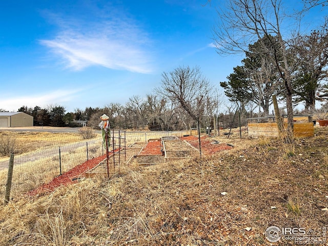 view of yard with a rural view, a vegetable garden, and fence