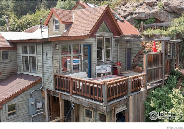 rear view of house featuring a shingled roof and a deck