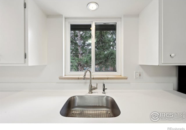 kitchen with white cabinets, light countertops, and a sink