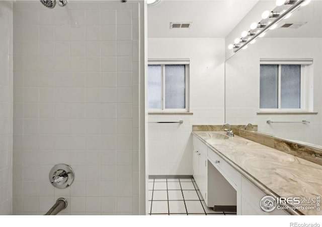 bathroom with tile patterned flooring, visible vents, tile walls, and vanity