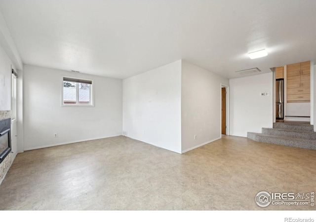 unfurnished room with baseboards, stairs, visible vents, and a glass covered fireplace