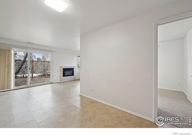 unfurnished living room featuring a glass covered fireplace and baseboards