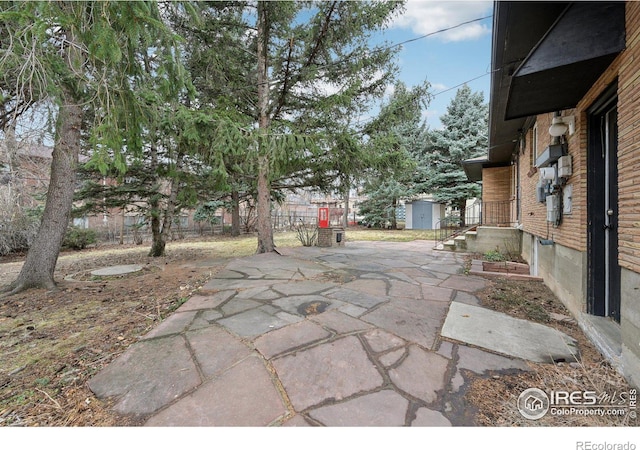 view of patio / terrace featuring a storage unit, an outdoor structure, and fence