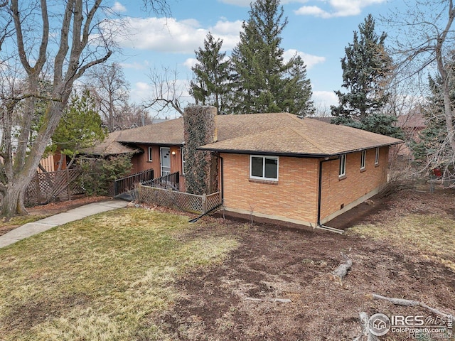 view of front of house featuring a shingled roof, a chimney, fence, a front yard, and brick siding