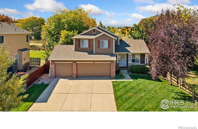 split level home with a front yard, concrete driveway, brick siding, and fence