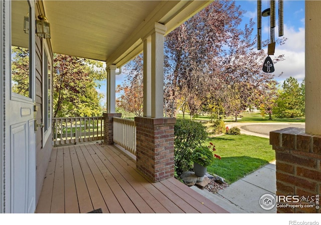 deck featuring covered porch and a lawn