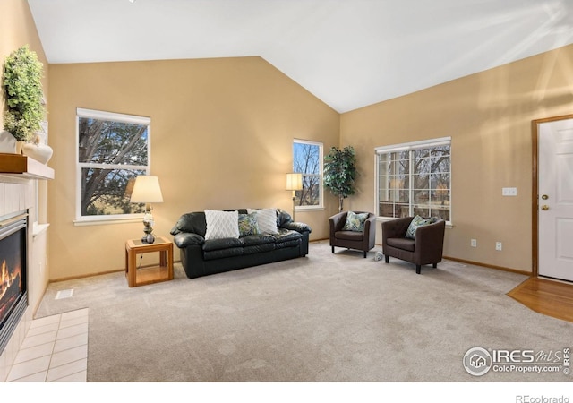 living area featuring lofted ceiling, baseboards, carpet flooring, and a tile fireplace