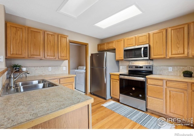 kitchen featuring appliances with stainless steel finishes, light countertops, a sink, and light wood-style flooring