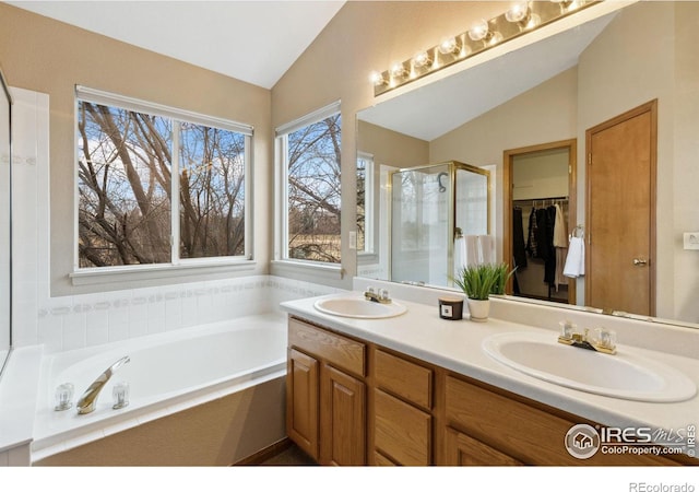 bathroom with vaulted ceiling, a stall shower, a sink, and a garden tub