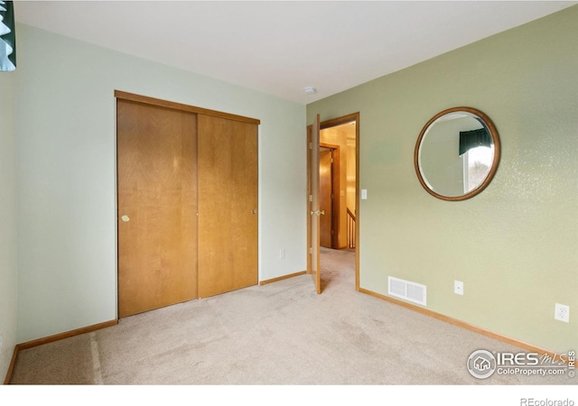 unfurnished bedroom with baseboards, a closet, visible vents, and carpet flooring