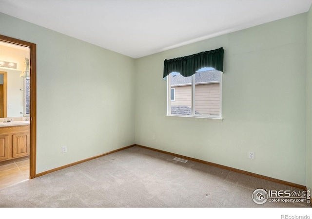 empty room with baseboards, visible vents, and light colored carpet