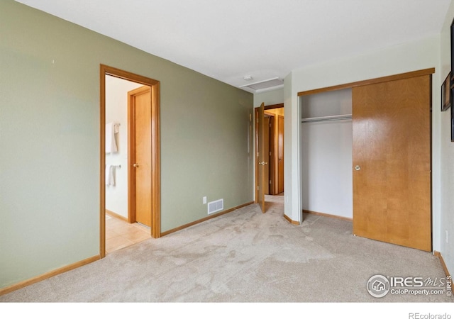 unfurnished bedroom featuring baseboards, visible vents, ensuite bath, carpet flooring, and a closet