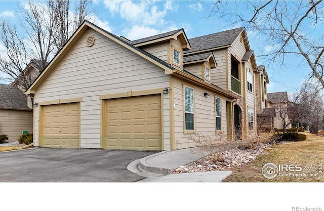 view of side of home with an attached garage and aphalt driveway