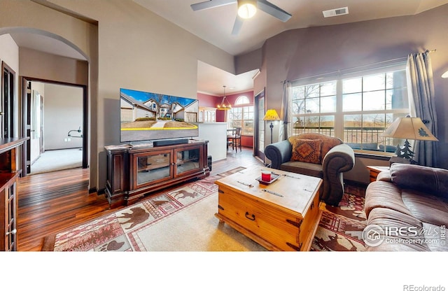 living area featuring visible vents, arched walkways, lofted ceiling, wood finished floors, and ceiling fan with notable chandelier