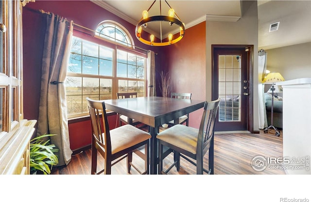 dining room with ornamental molding, a chandelier, and wood finished floors