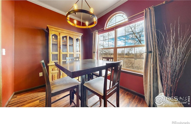 dining area featuring ornamental molding, a chandelier, baseboards, and wood finished floors