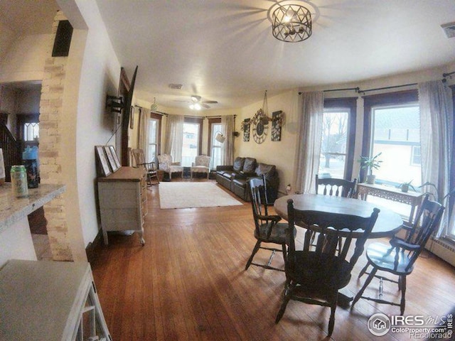 dining room with a ceiling fan, visible vents, and wood finished floors