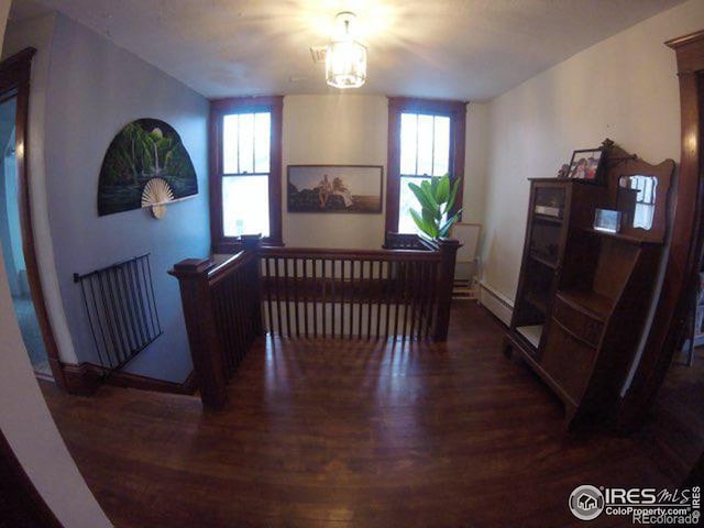 dining room featuring a baseboard heating unit, a healthy amount of sunlight, and wood finished floors