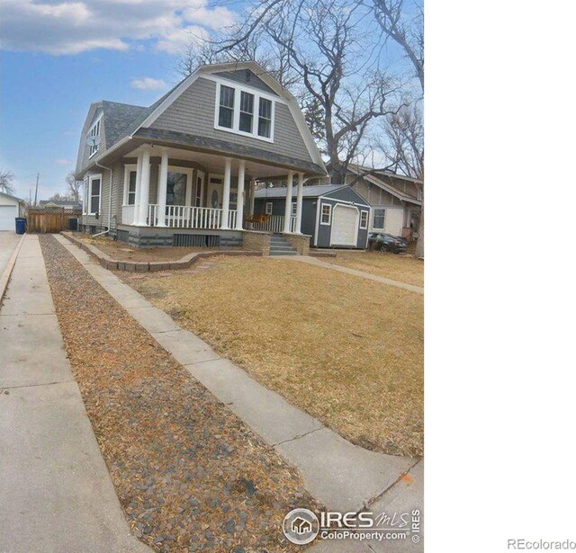 view of front of home featuring an outbuilding, a porch, a gambrel roof, a garage, and a front lawn