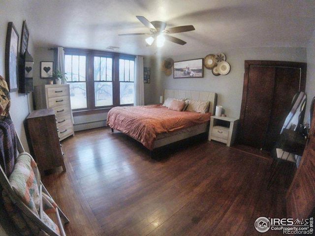 bedroom with ceiling fan, a baseboard radiator, and wood finished floors