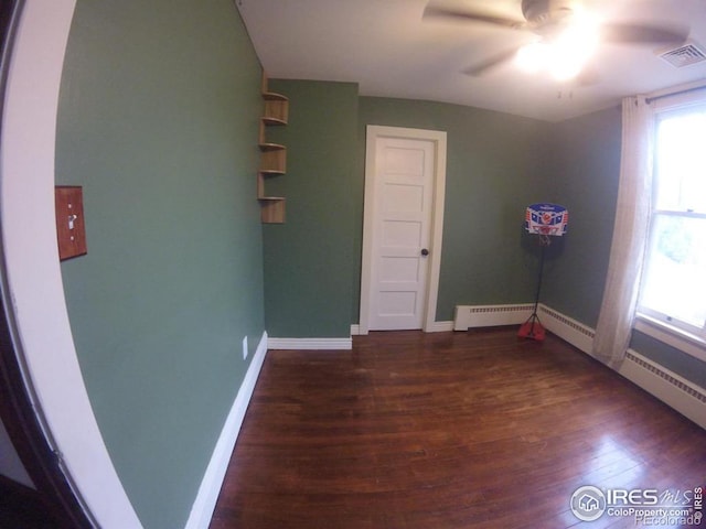 spare room featuring a ceiling fan, visible vents, baseboards, and wood finished floors