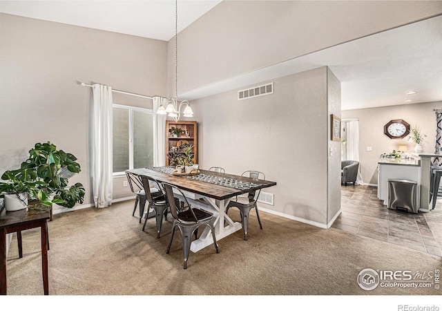 dining room featuring light carpet, an inviting chandelier, baseboards, and visible vents