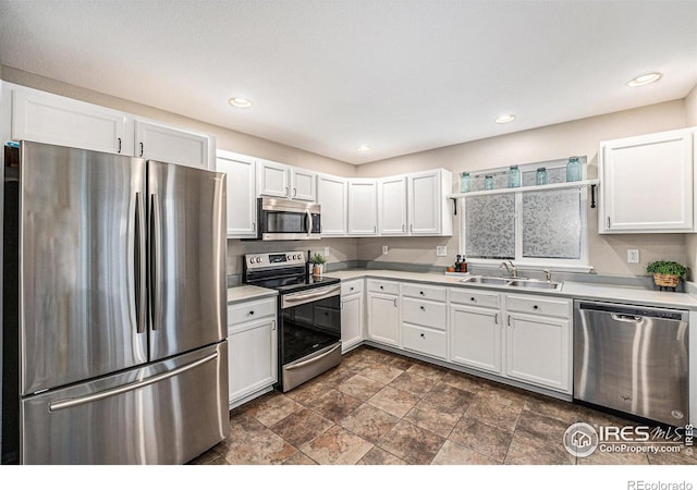 kitchen featuring recessed lighting, stainless steel appliances, a sink, white cabinets, and light countertops