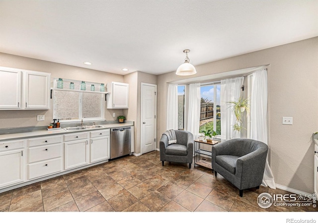 kitchen featuring light countertops, stainless steel dishwasher, white cabinetry, a sink, and baseboards