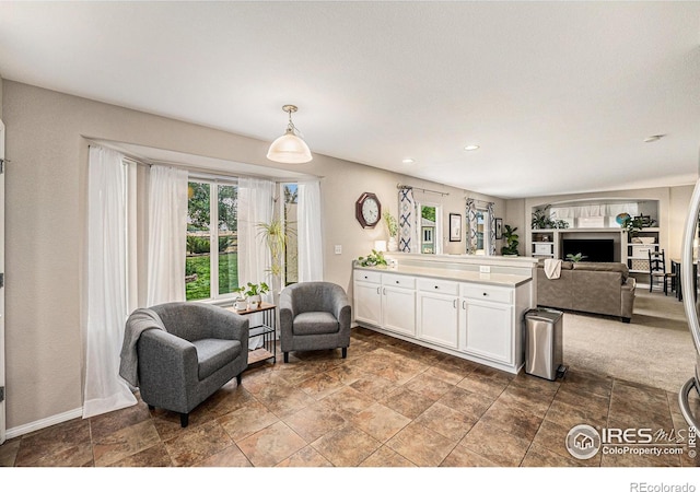 kitchen with light countertops, hanging light fixtures, open floor plan, white cabinets, and a peninsula