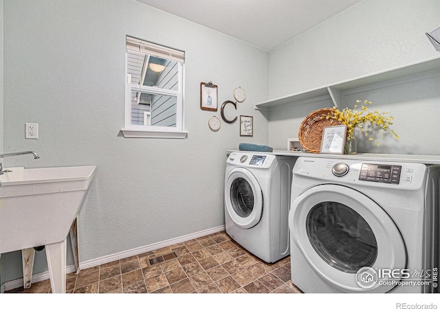 laundry room featuring laundry area, visible vents, baseboards, washing machine and clothes dryer, and stone finish flooring